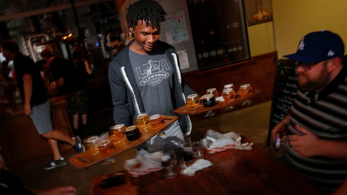 A server delivers an order at Los Angeles Ale Works in Hawthorne. The brewery's minimum-wage employees get a raise to $10.50 an hour on Jan. 1.