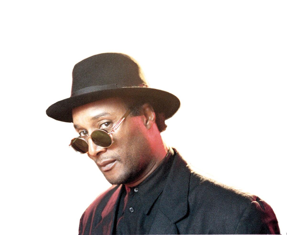A man in a black suit, hat and sunglasses