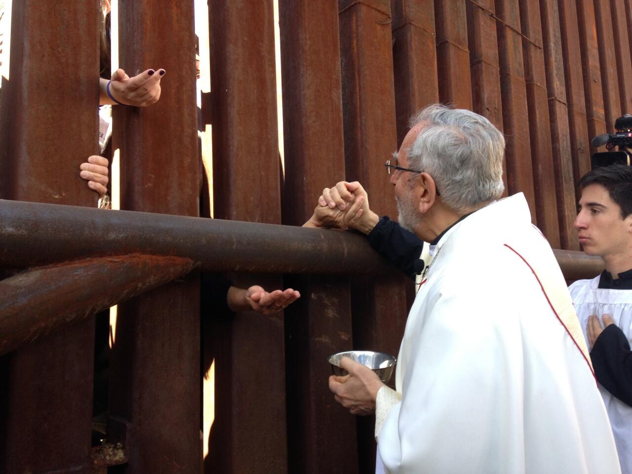 Tucson Bishop Gerald Kicanas gives Communion to people on the Mexican side of the border fence.