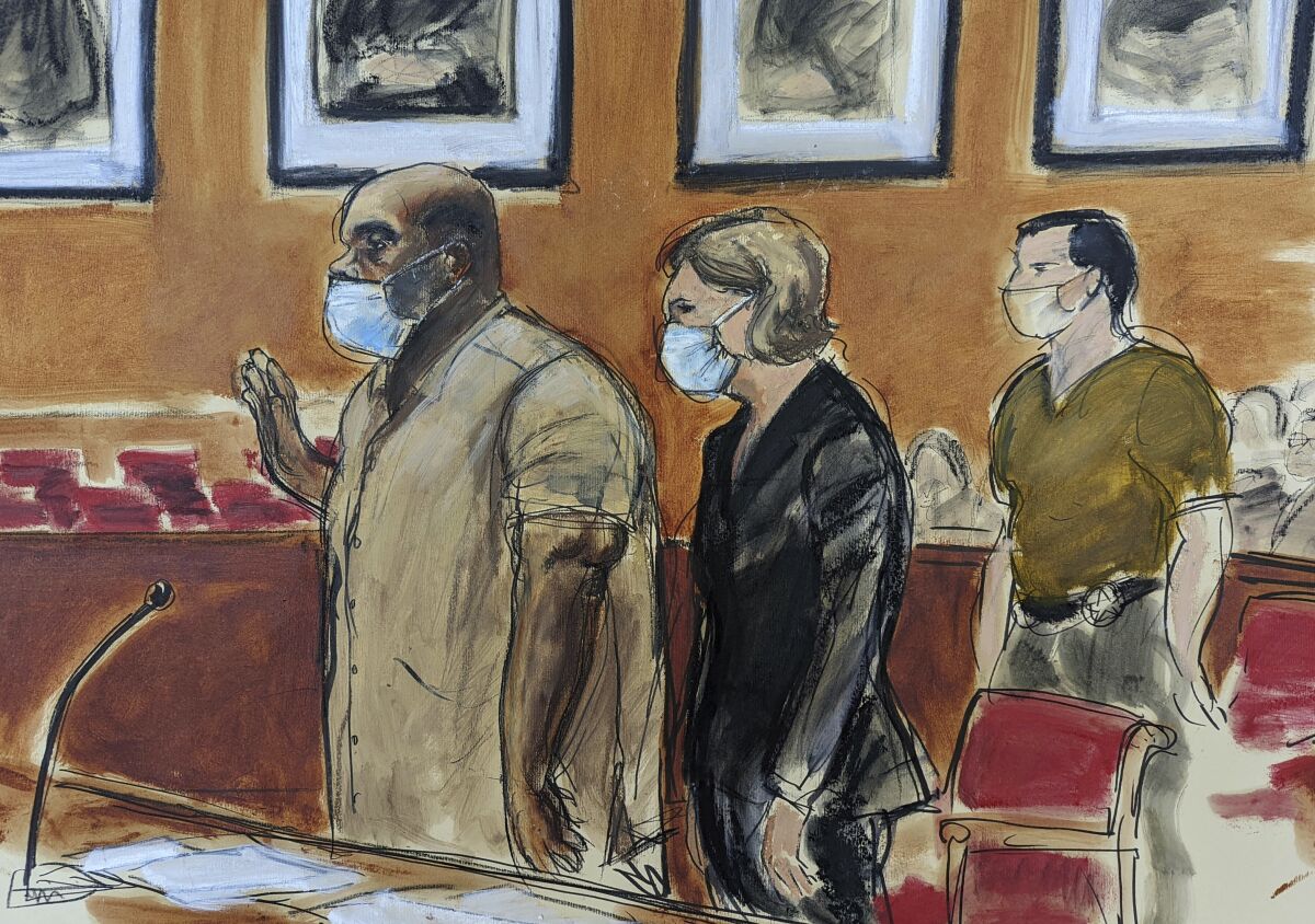 In this courtroom sketch, Frank James, left, the man accused in a mass shooting on a subway train in the Brooklyn borough of New York, is sworn-in during his arraignment in federal court, Friday, May 13, 2022, in New York. His defense attorney Mia Eisner-Grynberg is at center. James, 62, is facing charges of committing a terrorist attack or other violence against a mass transportation system and discharging a firearm during a violent crime. Both counts carry a maximum sentence of life in prison. (AP Photo/Elizabeth Williams)