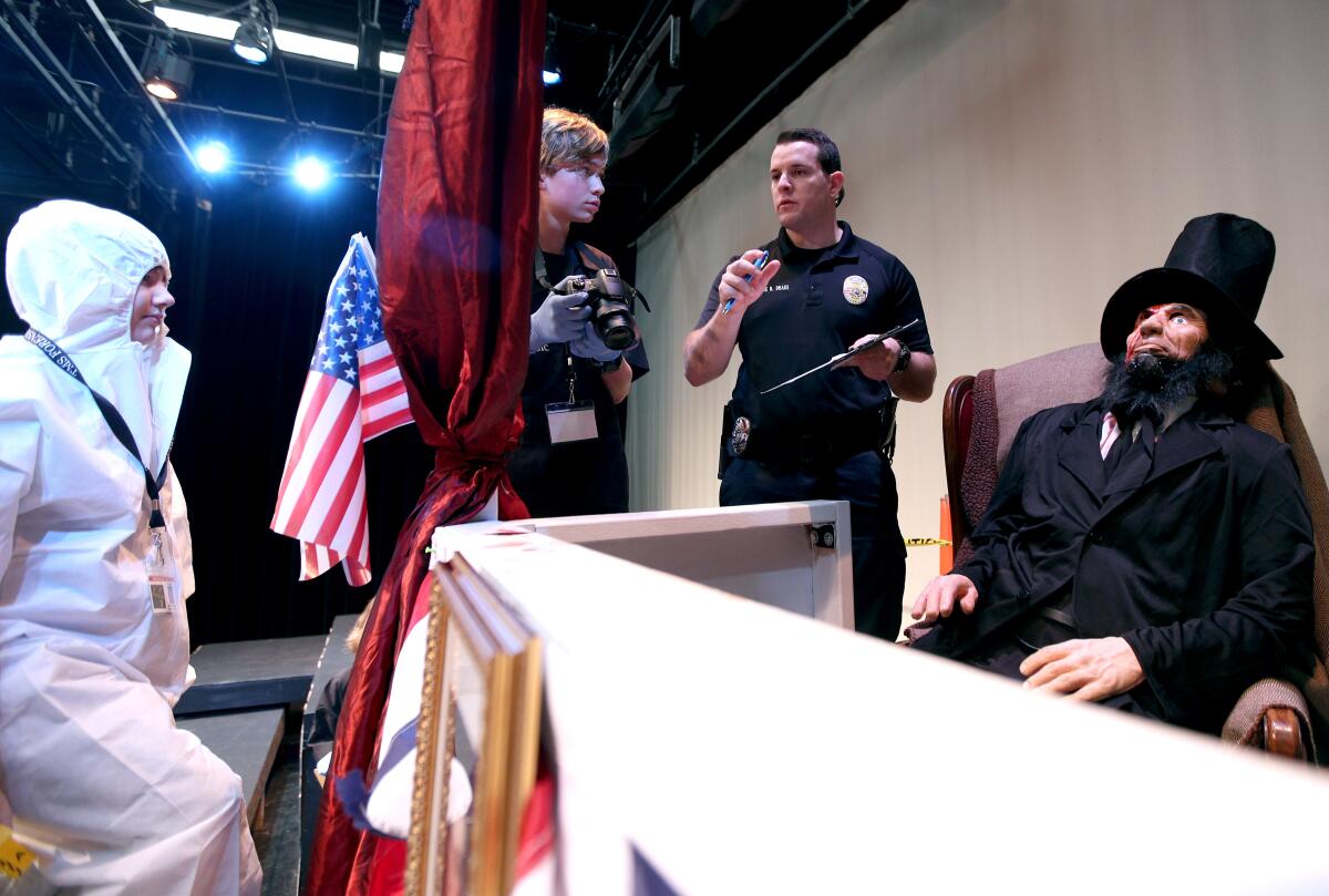 Laguna Beach police Det. Brandon Drake helps Thurston Middle School forensics students, including "coroner" Maris Morgan and crime scene photographer Carter McKinzie, conduct a mock investigation of the assassination of Abraham Lincoln.