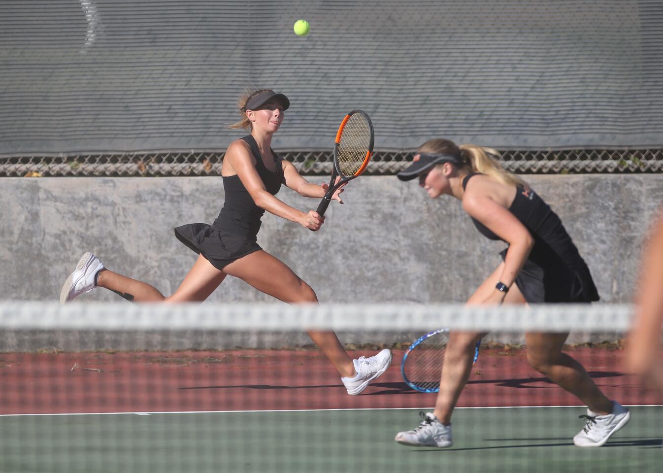 Huntington Beach doubles player Daniella Pokorny runs down a baseline lob as teammate Emily Gray gets out of the way during Wave League tennis against cross town rival Edison on Tuesday.