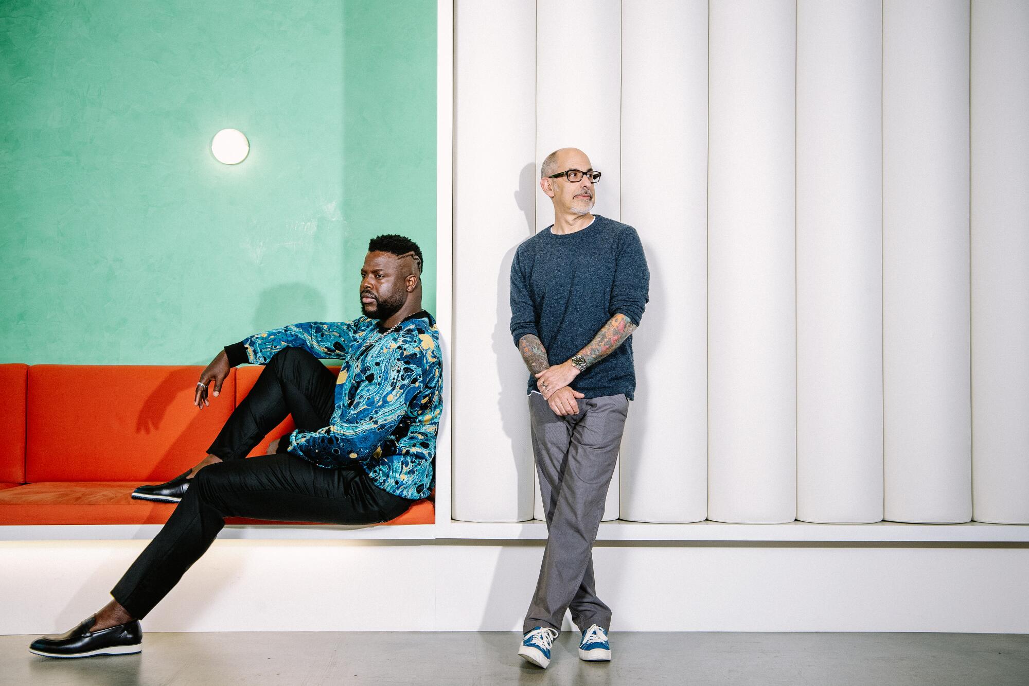 Two men occupy a monochrome room with a brightly colored alcove.