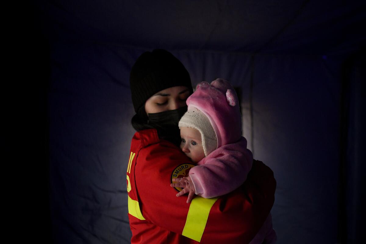 Una empleada del Cuerpo de Inspectores de Situación de Emergencia tranquiliza a una bebé 