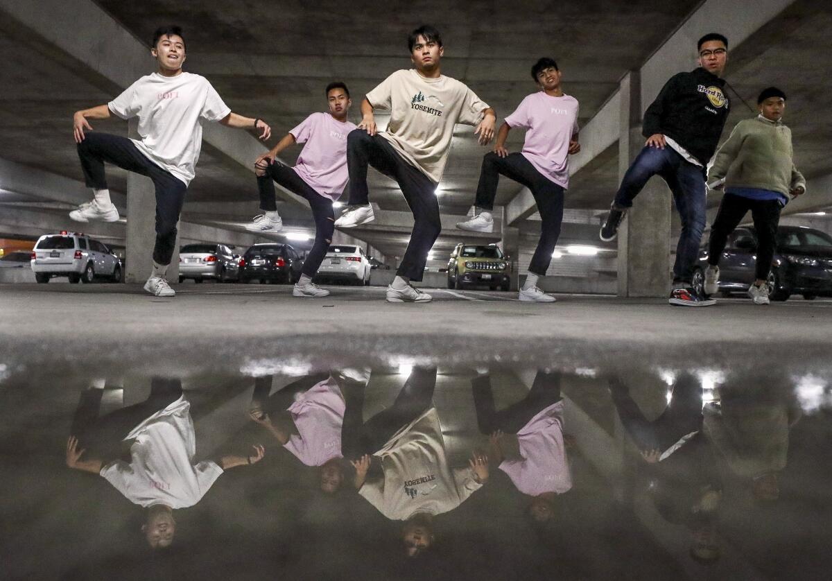 A hip-hop dance group is reflected in a puddle as they perform during an end of the year choreography project put on by the SDSU Vietnamese Student Organization Modern, a collegiate hip-hop dance troupe, in a parking garage on the SDSU campus on Thursday, Dec. 5, 2019.