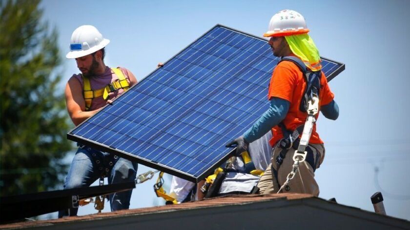 Workers install a solar panel array on a home in San Diego in 2017.