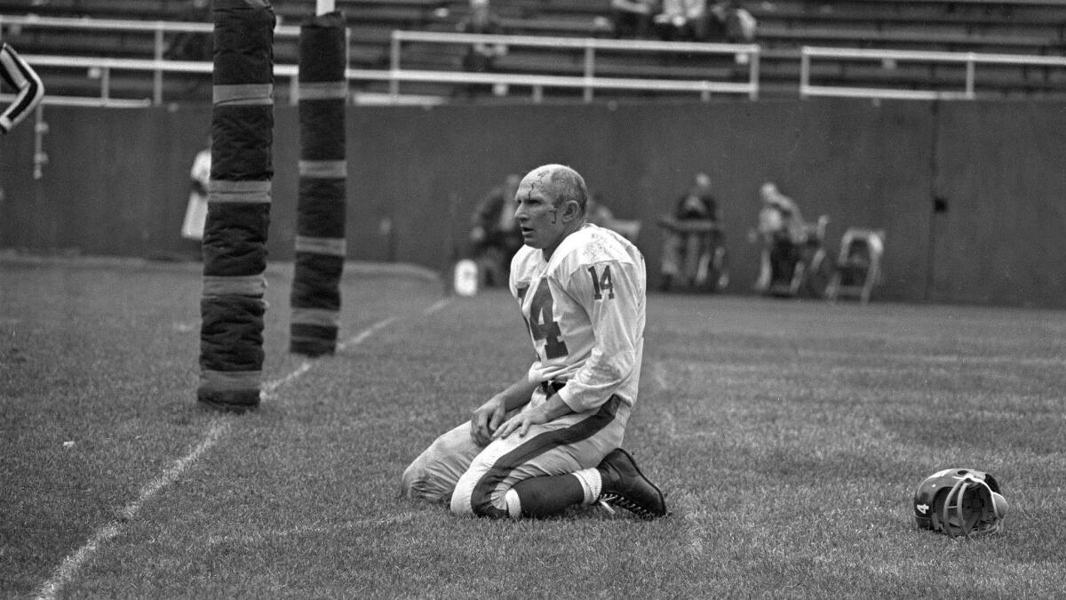 New York Giants quarterback Y.A. Tittle kneels, bloodied, on the field after being hit hard during a game against the Pittsburgh Steelers in 1964.
