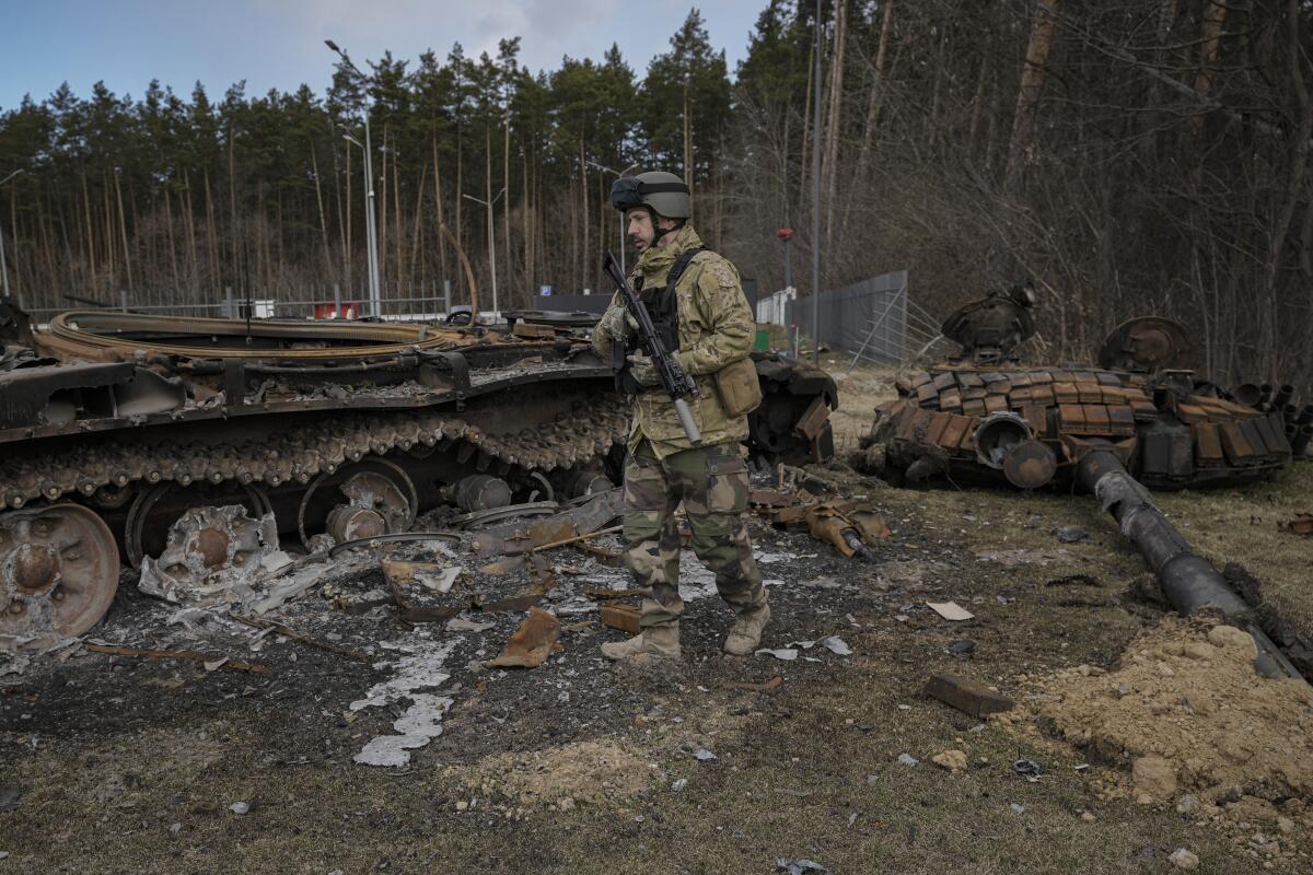 FILE - A Ukrainian serviceman walks next to the wreck of a Russian tank in Stoyanka, Ukraine, March 27, 2022. With Russian hopes for storming Kyiv and other major cities in northern Ukraine dashed by stiff resistance, Moscow has refocused its efforts on the country’s east, seeking to make gains there and use them to dictate its terms in talks on ending the conflict. (AP Photo/Vadim Ghirda, File)