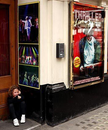 A young girl cries in front of the Lyric Theatre in London next to a poster for "Thriller Live," a musical featuring songs of Michael Jackson.