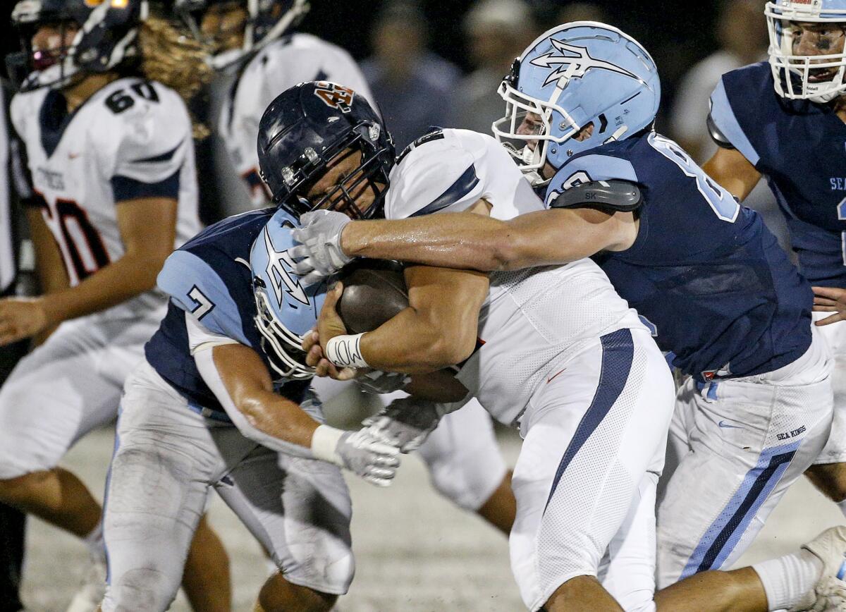 Corona del Mar defenders Colin Pene (7) and Breck Clemmer (88) converge on running back Rocco Burdett for no gain.