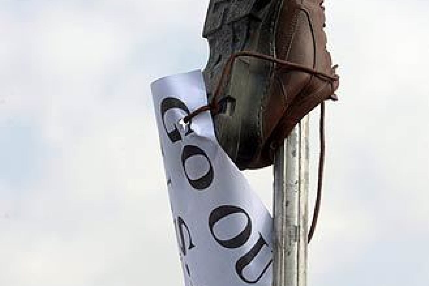 A shoe and a sign reading "Go out USA" is placed on a pole in Sadr City as Iraqis protest President Bush's farewell visit and the arrest of an Iraqi journalist who threw his shoes at the president during a news conference in Baghdad.