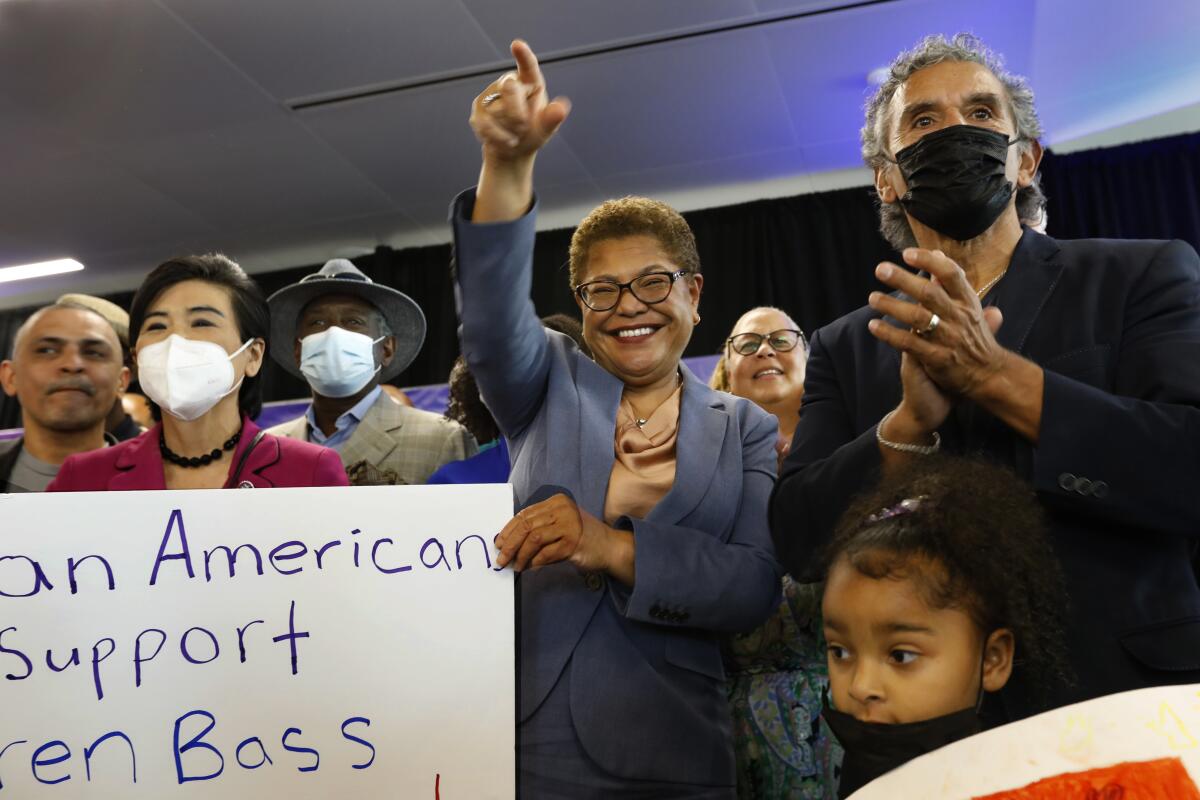 A woman in a suit stands with supporters holding a sign