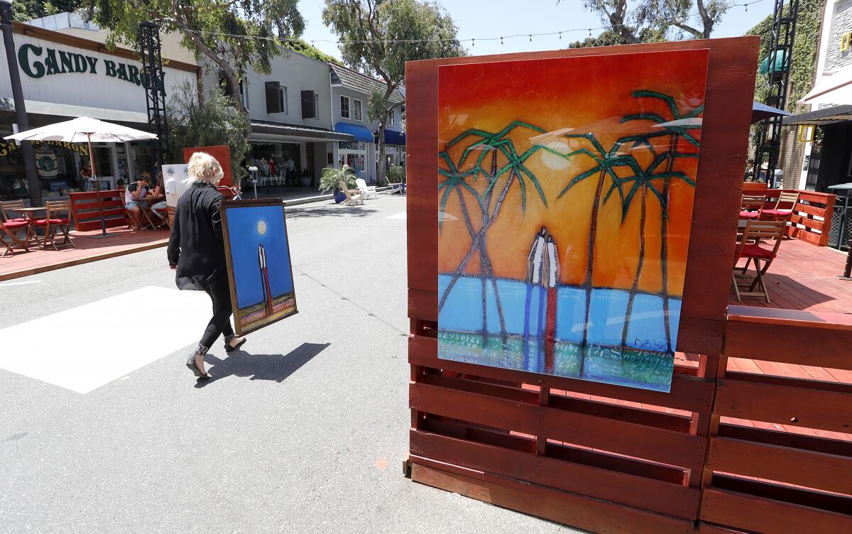 Diane DeBilzan hangs art from the DeBilzan Gallery on the Promenade on Forest in downtown Laguna Beach.