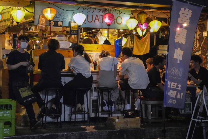 People gather at a bar after government imposed 8 p.m. closing time for restaurants and bars under Tokyo's fourth state of emergency Saturday, July 17, 2021, in Tokyo. The latest state of emergency has asked restaurants and bars to close by 8 p.m., if not entirely. This has pushed people to drink outside, although many bars remain open and bustling with customers who are defying the rules and expressing frustration and indifference. (AP Photo/Kiichiro Sato)