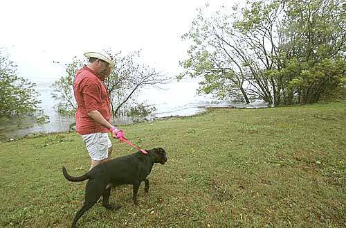 Bryan Redden holds on to his hat as he walks his dog, Molly, in Lake Charles, La.