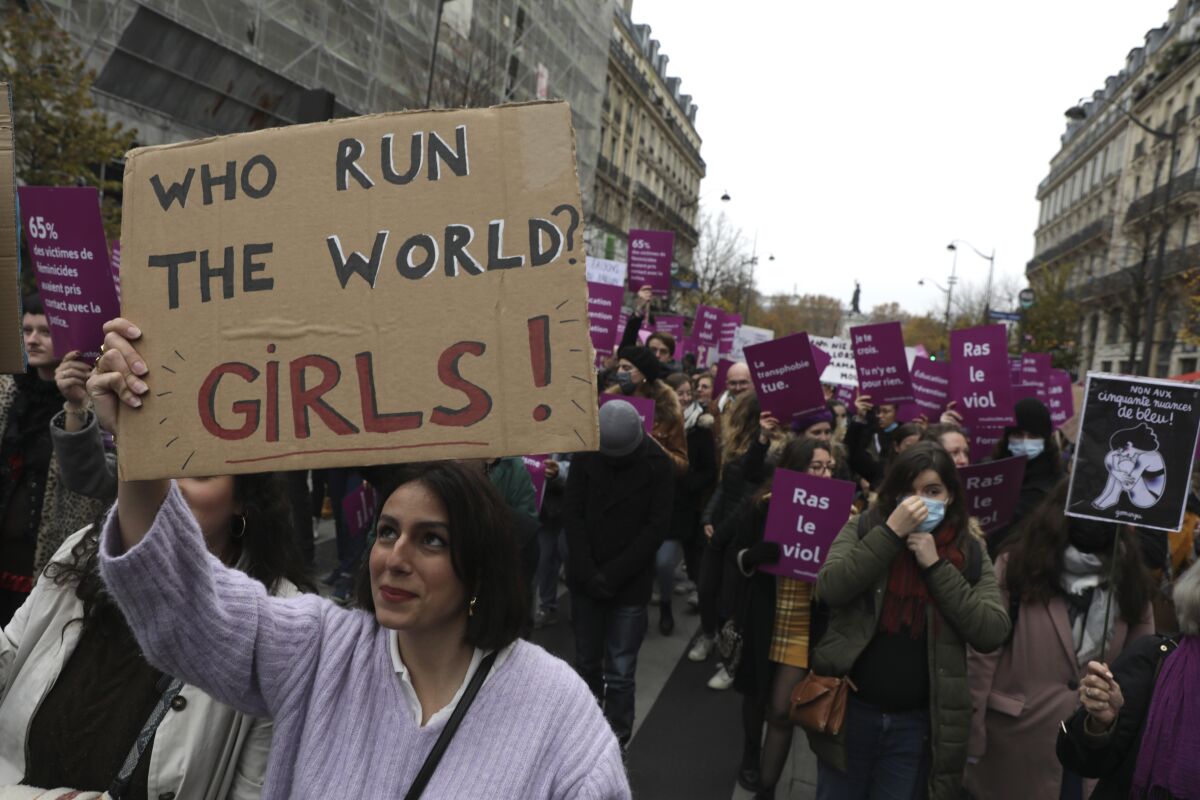 A woman holds up a sign reading "Who run the world? Girls!" during a march in Paris