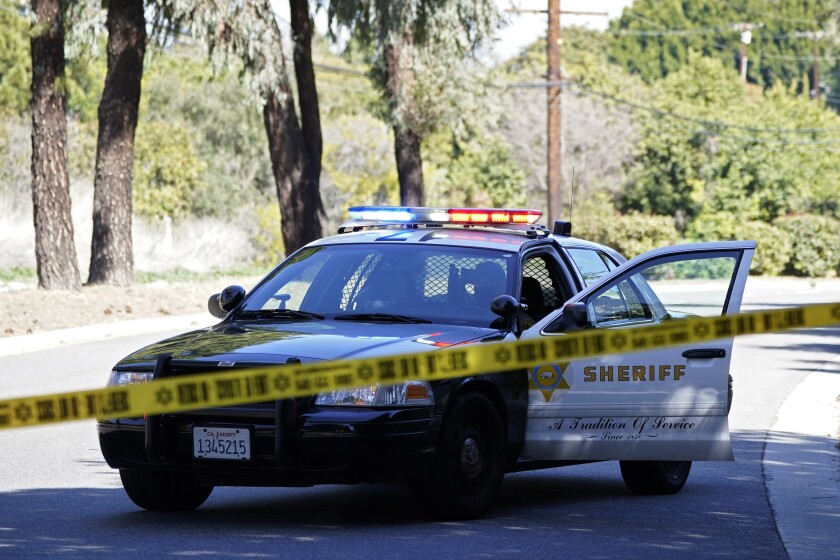 FILE - In this Feb. 23, 2021, file photo, a police car blocks a road in a suburb of Los Angeles. The Associated Press says it will no longer publish the names or photographs of people charged with minor crimes, in a recognition of how such stories can have a long, damaging afterlife on the Internet. (AP Photo/Ashley Landis, File)