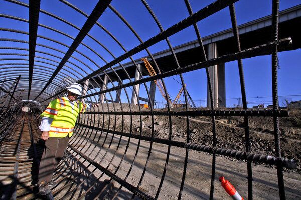 Dennis Wolcott of the Port of Long Beach makes his way along a rebar tube, which will be used to create pylons for construction of the new Gerald Desmond bridge. The old bridge can been seen at right.