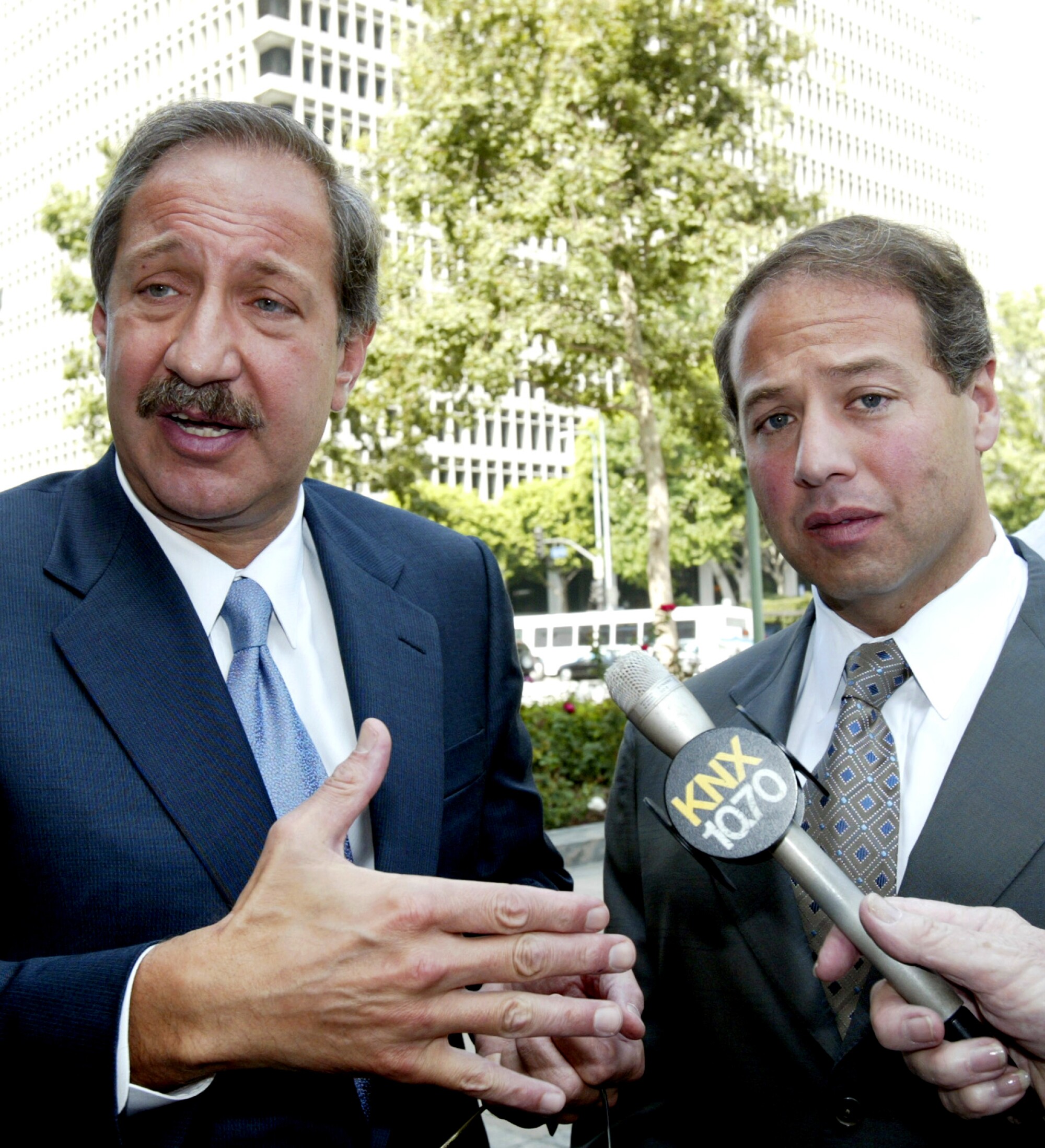 Two men stand before a microphone.