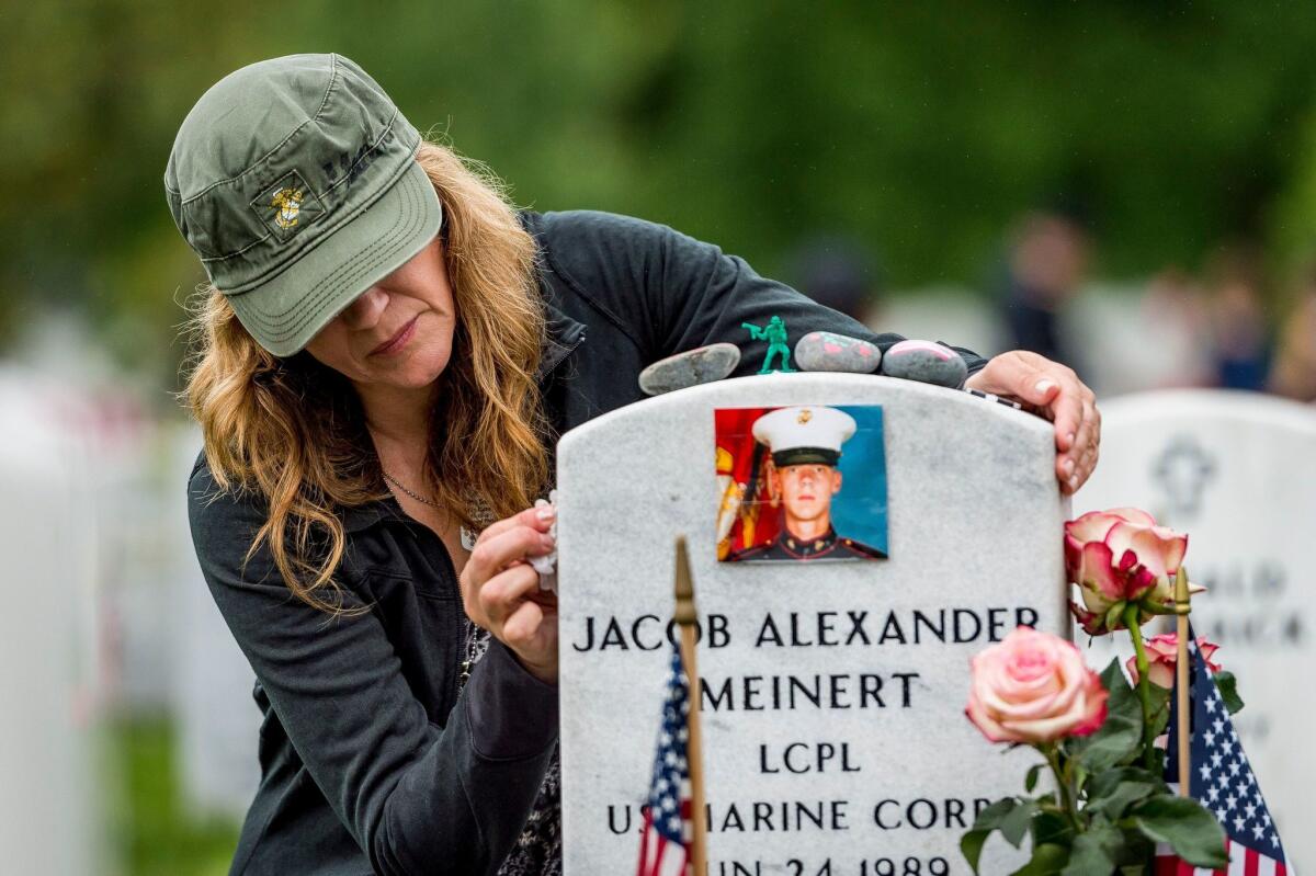 Krista Meinert of Fort Atkinson, Wis., cleans the headstone of her son, Jacob, who was killed in Afghanistan, at Arlington National Cemetery.