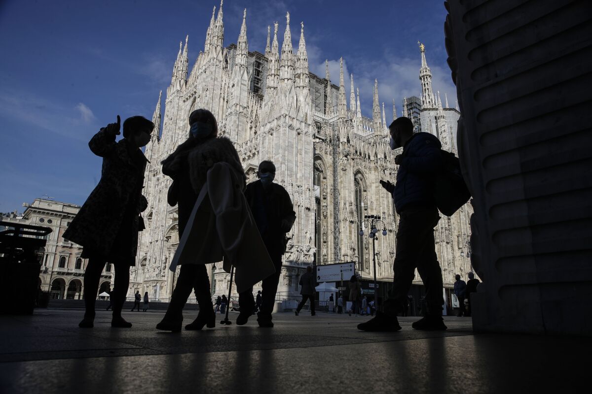 People wear masks to curb the spread of COVID-19 as they walk next to the Duomo gothic cathedral, in Milan, Italy, Friday, Oct. 16, 2020. Italian health officials have declared the country in an "acute phase" after the country set records for new daily cases higher than even during the March-April peak, when the death toll surged well over 900 in one 24-hour period. Regions have urged the government to allow distance learning for the upper grades of high school, to take pressure off public transport which remains a major concern due to crowding. (AP Photo/Luca Bruno)
