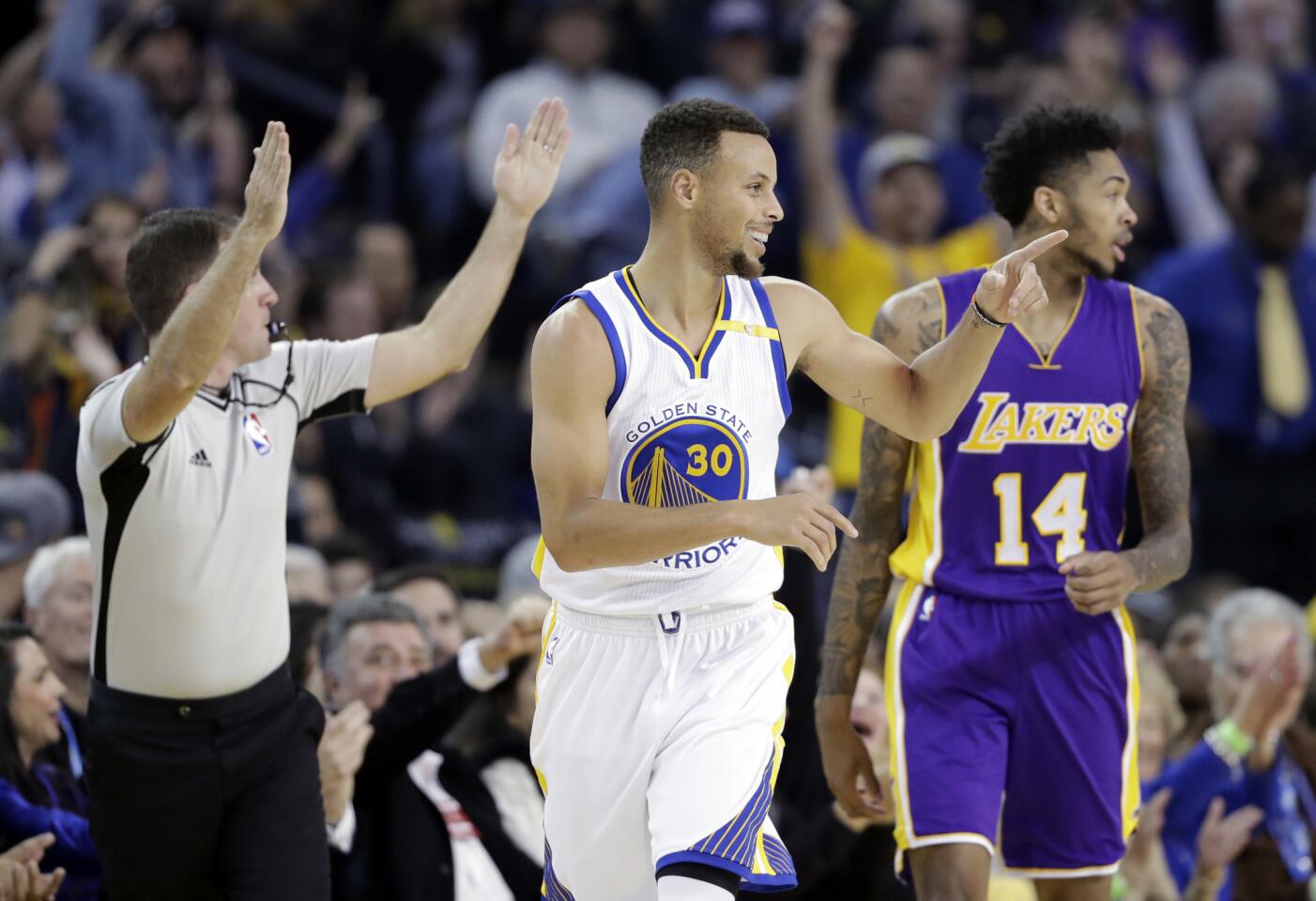 Warriors point guard Stephen Curry (30) acknowledges a teammate after scoring against the Lakers during the first half.