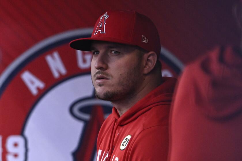 Los Angeles Angels' Mike Trout looks over in the dugout before a baseball game.