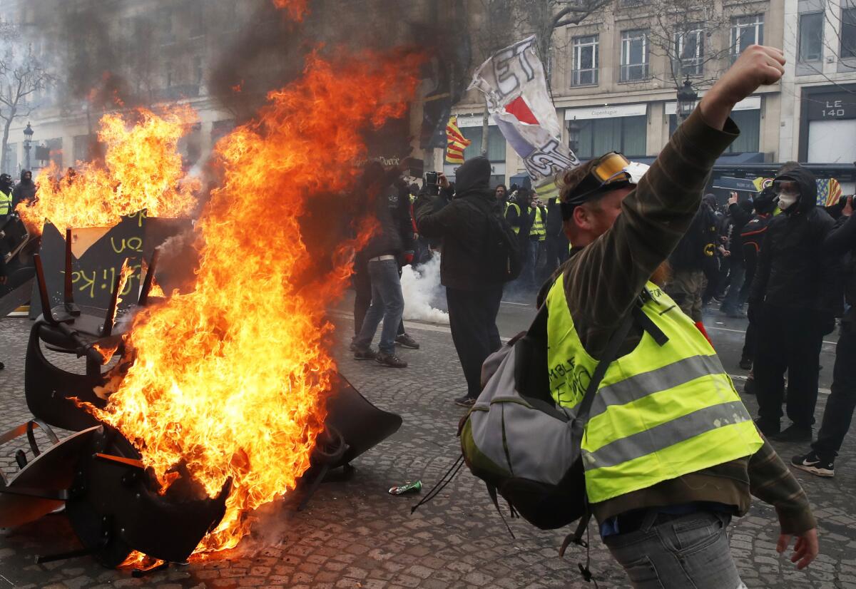 Un manifestante corea lemas delante de una barricada en llamas durante una protesta del movimiento de los "chalecos amarillos" en París, el 16 de marzo de 2019. (AP Foto/Christophe Ena)
