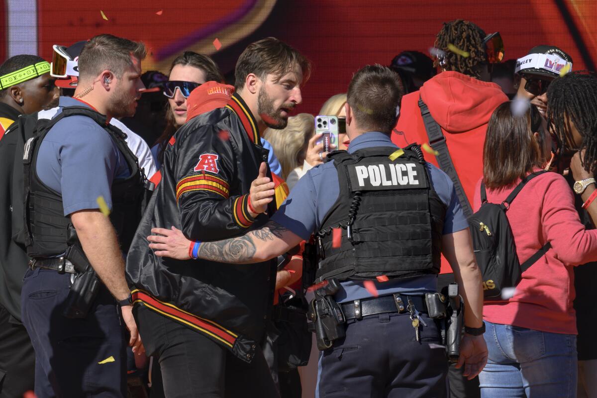 Police escort Kansas City Chiefs tight end Noah Gray and his teammates off the stage after a shooting.