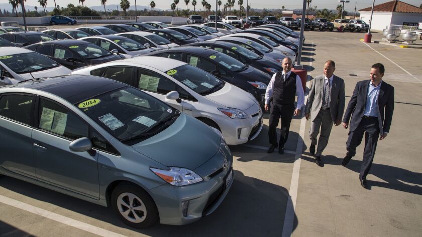 Roger Hogan Jr., Roger Hogan and Stephen Hogan at their Toyota of Claremont dealership with some of the Prius vehicles they say were not safe to drive because of a defect in their power system. The dealer has sued Toyota; a trial date is set for next year.