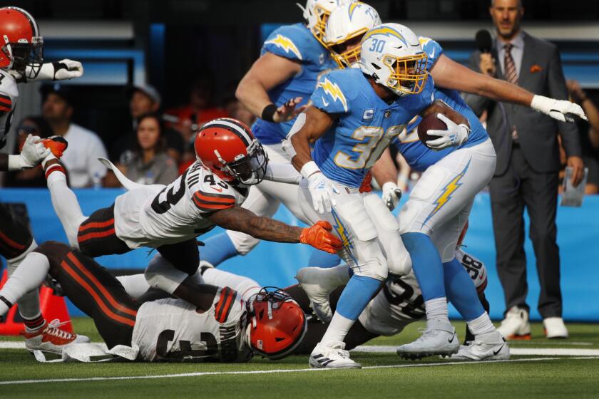 INGLEWOOD, CA - OCTOBER 10, 2021: Los Angeles Chargers running back Austin Ekeler (30) breaks free from the tackle attempt by Cleveland Browns free safety John Johnson (43) in the fourth quarter at SoFi Stadium on October 10, 2021 in Inglewood, California.(Gina Ferazzi / Los Angeles Times)