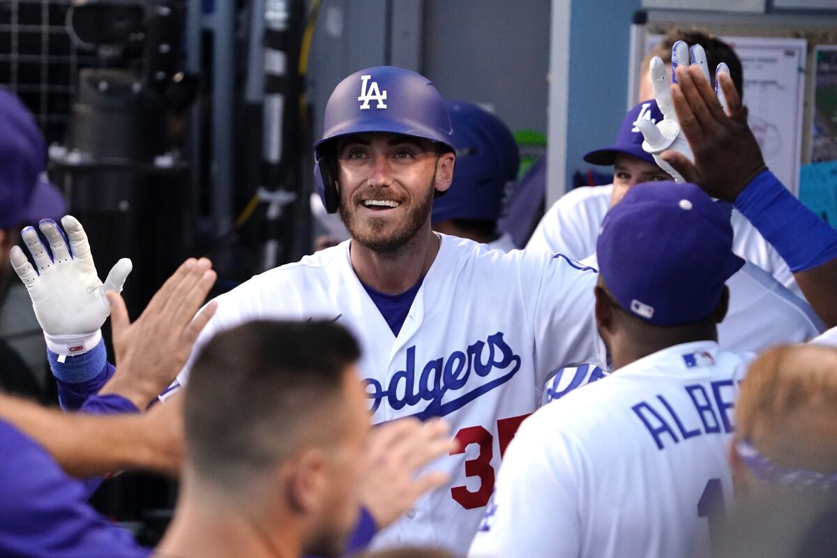 Cody Bellinger celebrates with his Dodgers teammates in the dugout after hitting a solo home run.