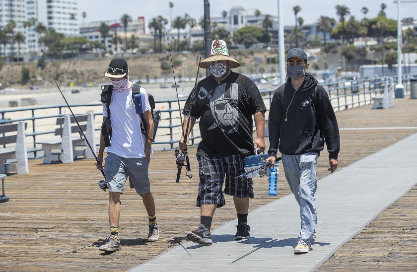 Friends Adrian Sanchez, left, Matthew Gonzalez and Justice Arreola arrive at the Santa Monica Pier to fish.