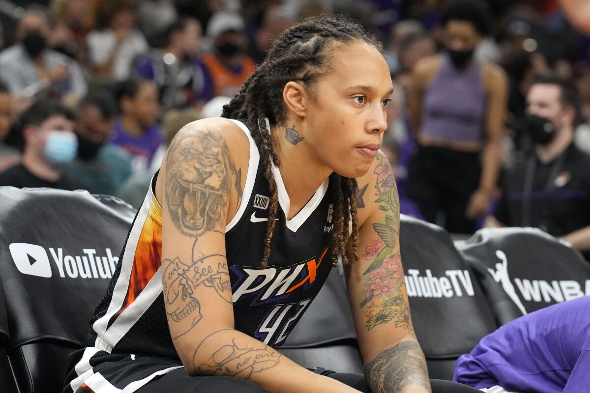 WNBA star Brittney Griner sits on the bench during a game.
