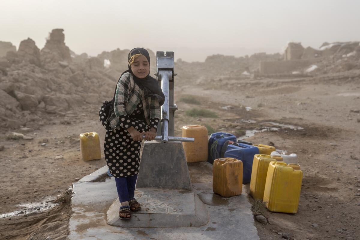 An Afghan girl fills containers with water from a well during a sandstorm.