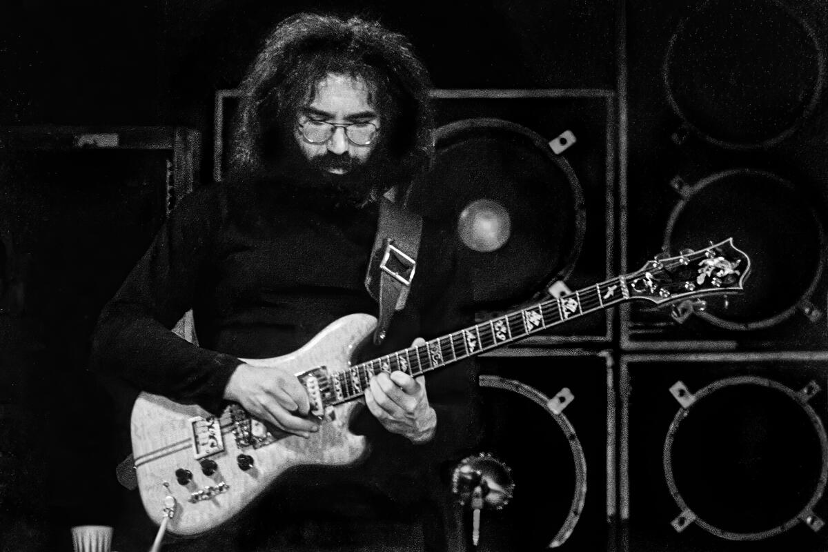 Jerry Garcia playing guitar in front of amplifiers
