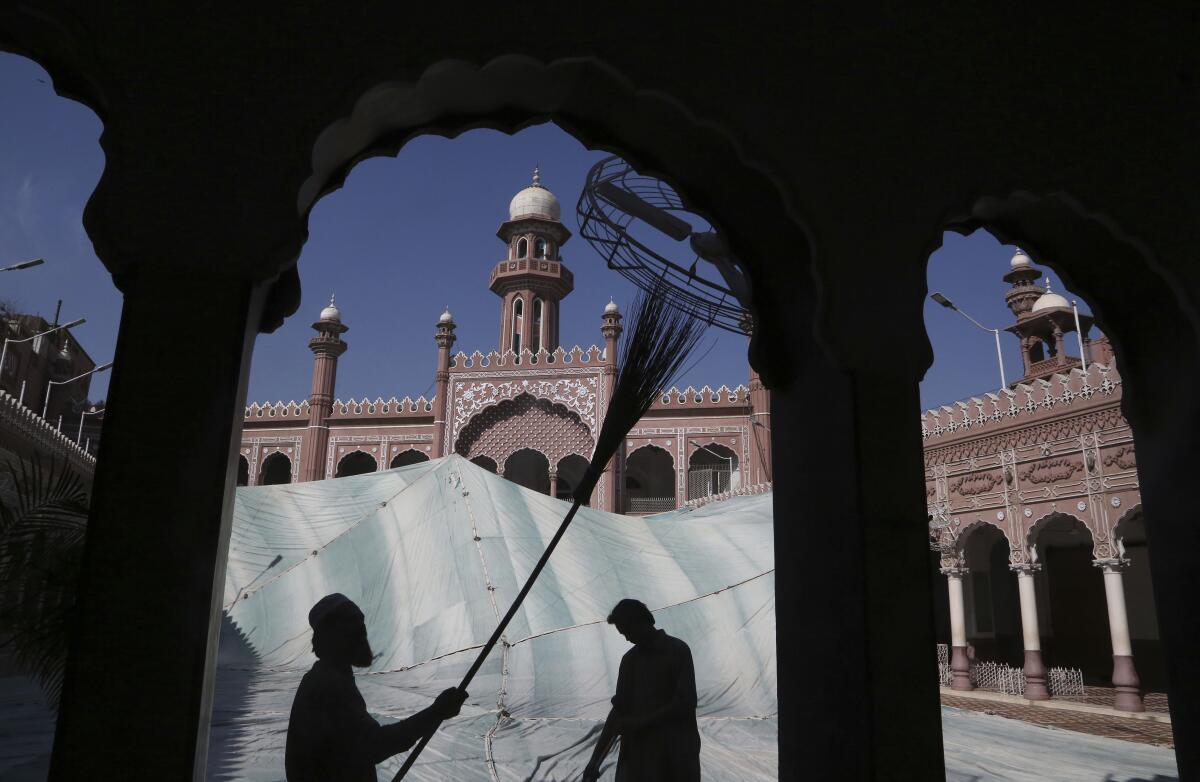 FILE - In this, Friday, April 9, 2021, file photo, volunteers clean the outer areas of the historic Mohabat Khan Mosque ahead of the upcoming Muslim fasting month of Ramadan, in Peshawar, Pakistan. Muslims are facing their second Ramadan in the shadow of the pandemic. Many Muslim majority countries have been hit by an intense new coronavirus wave. While some countries imposed new Ramadan restrictions, concern is high that the month’s rituals could stoke a further surge. (AP Photo/Muhammad Sajjad, File)