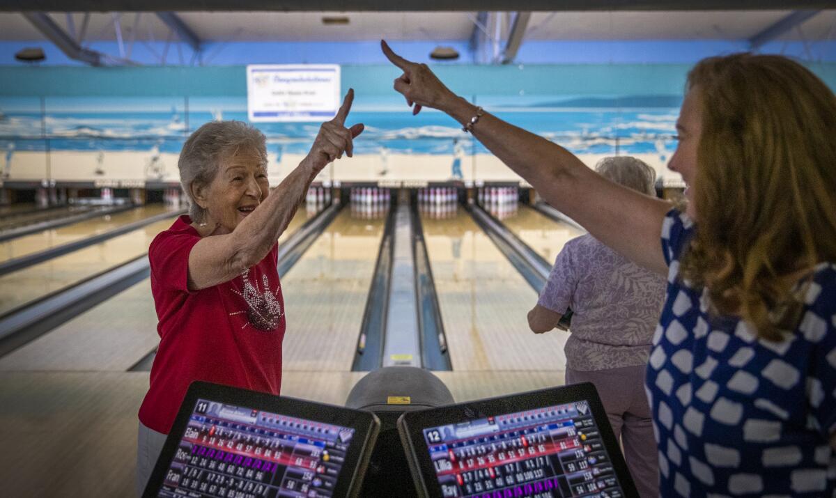 Rayanne Weiss, a la derecha, felicita a su madre, Lillian Solomon, quien cumple 100 años este 18 de septiembre y acaba de hacer una chuza durante un partido en la Liga Sénior de Verano en El Segundo.