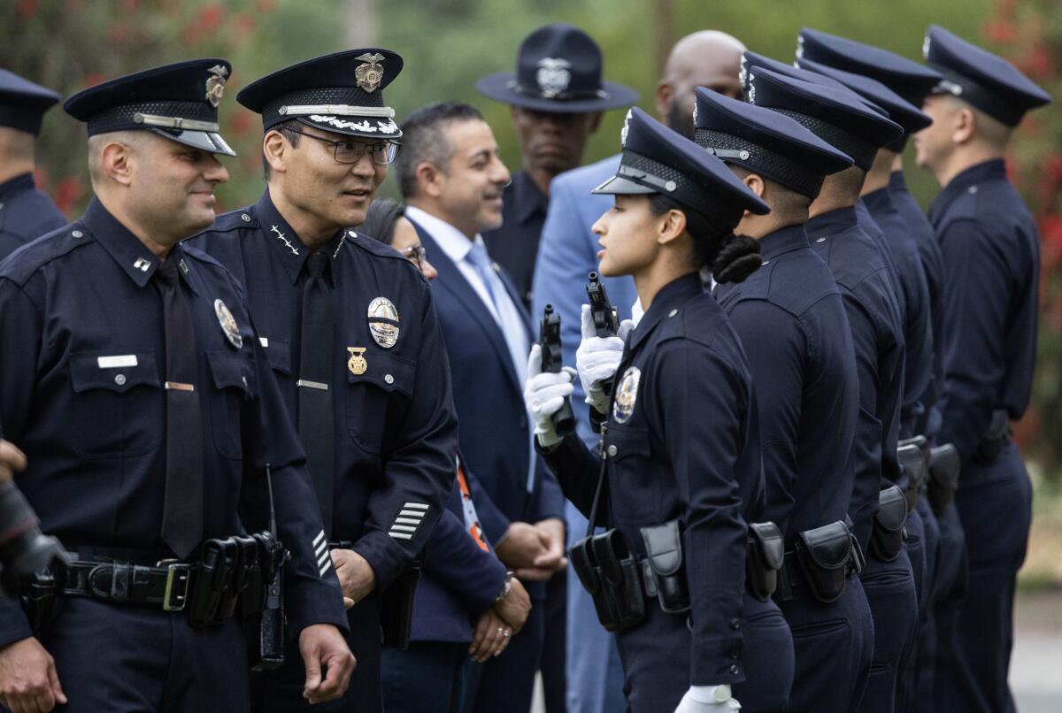 LAPD Interim Police Chief Dominic Choi, second from left, addressing a line of officers in uniform