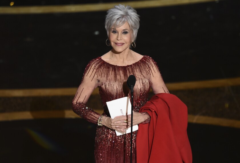 Jane Fonda holds an Oscars envelope onstage.