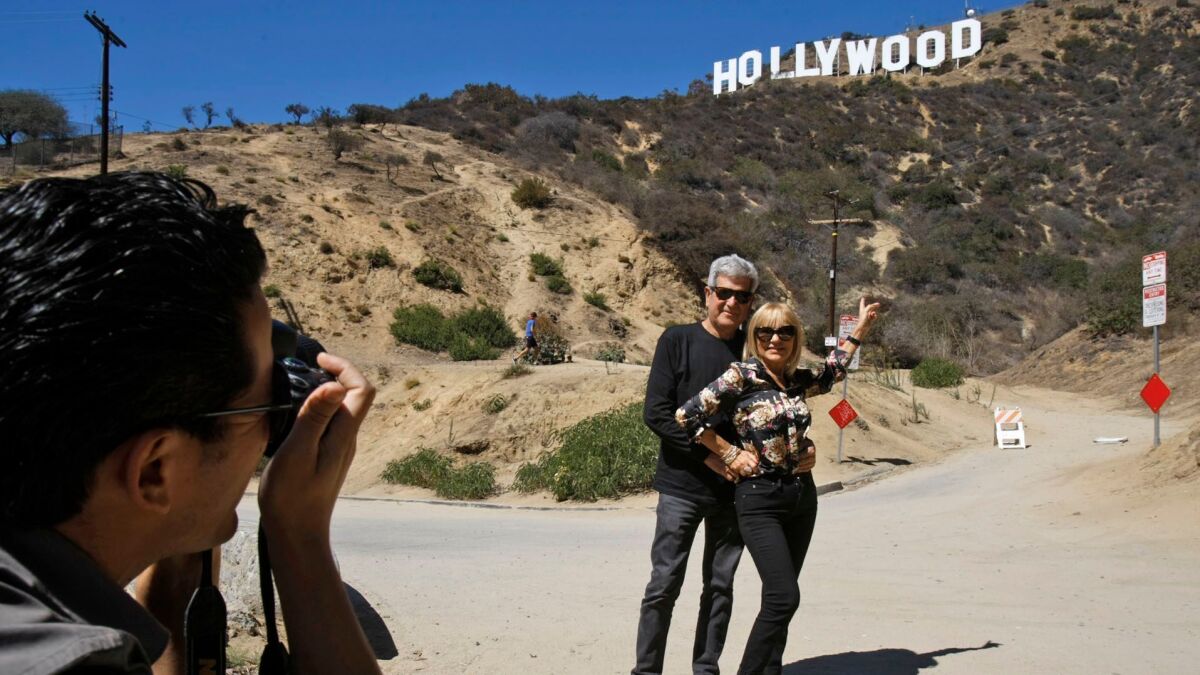 Spanish tourists Silvestre Llobet and his wife, Elena Domenech, are photographed by their son, Alejandro Llobet, in front of the Hollywood sign in 2013.