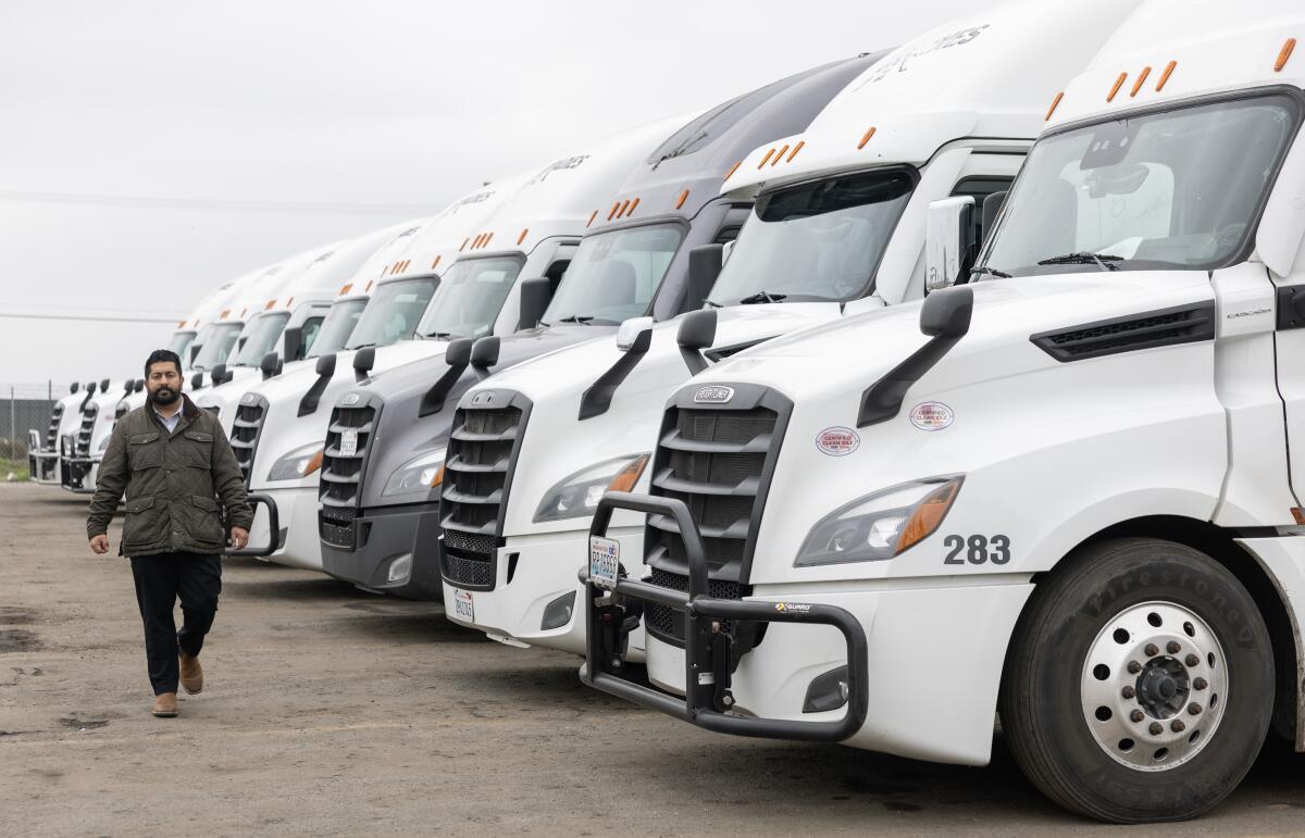A person walks by a row of white trucks.
