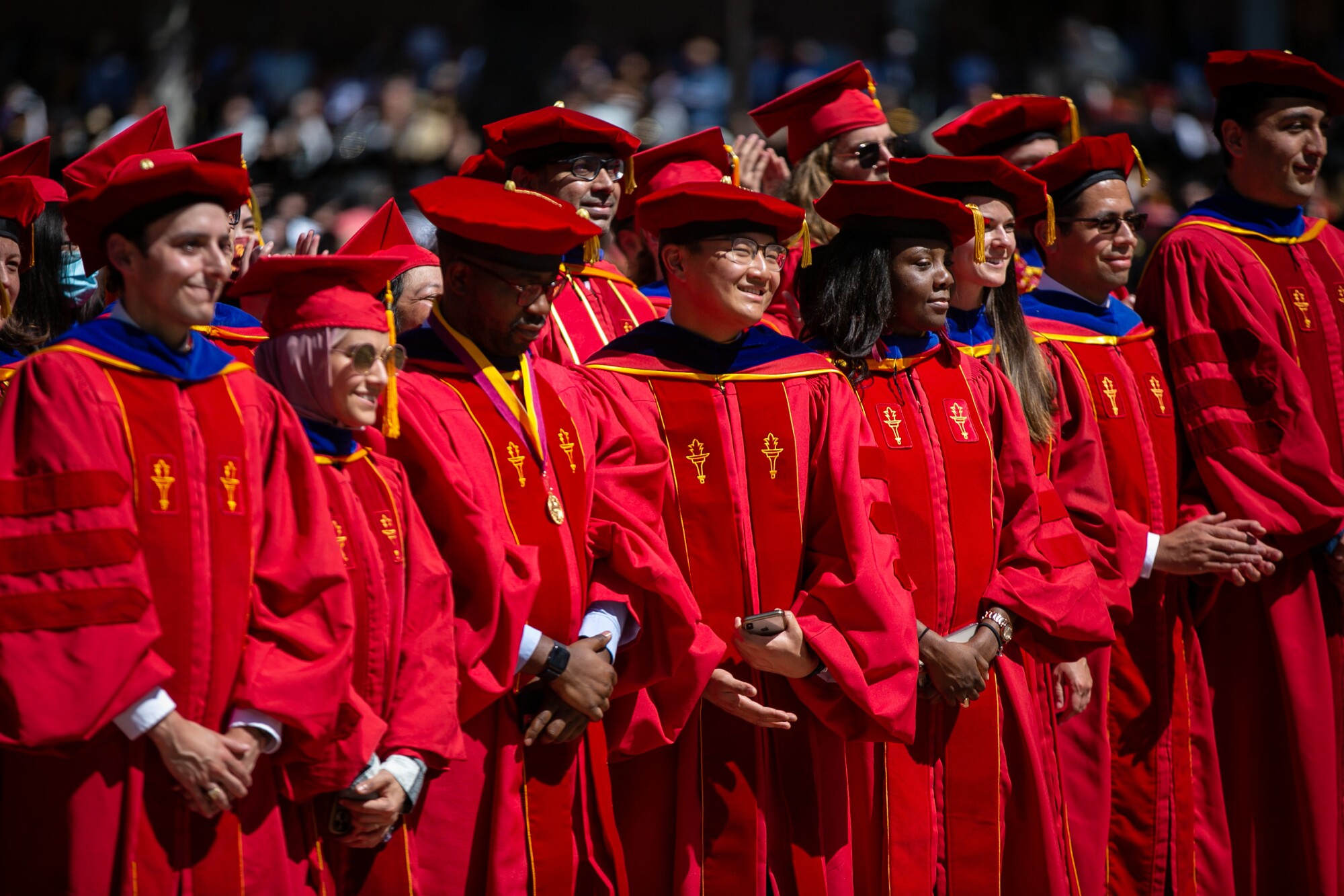 USC graduates smile in red robes.