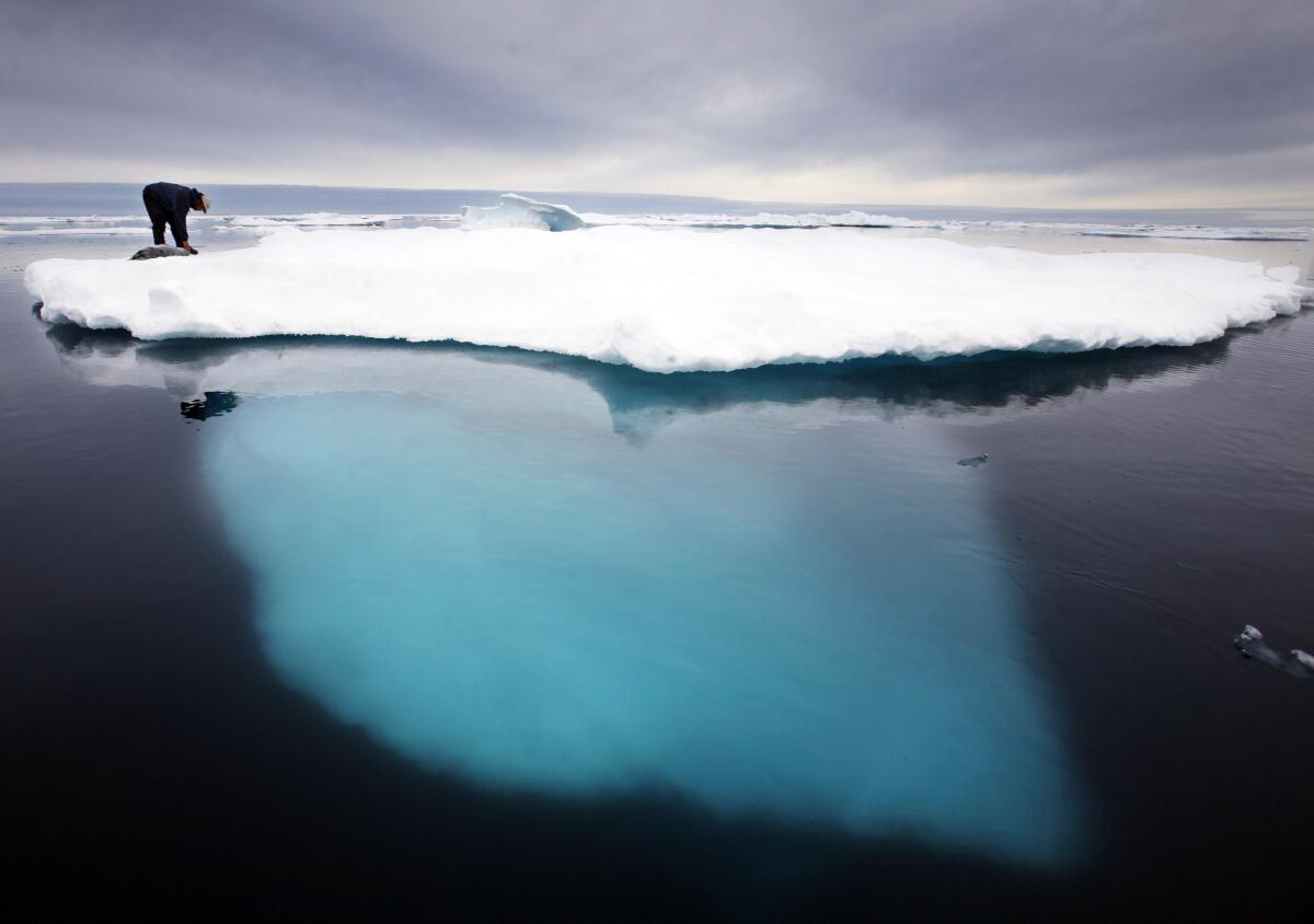 Inuit seal hunter atop a melting iceberg