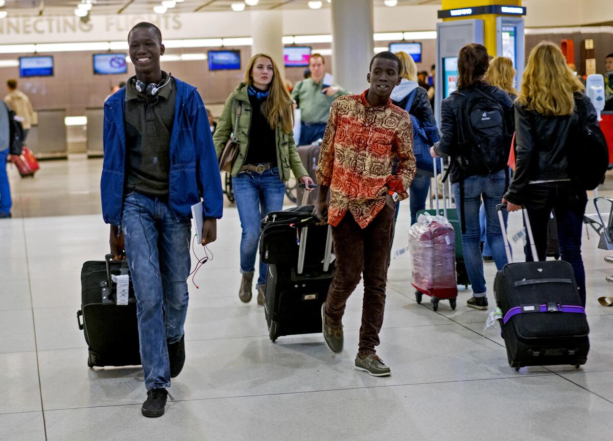 Johnson Nellon, left, and his brother Thomas Nellon smile at their mother as they arrive from Liberia at John F. Kennedy International Airport.