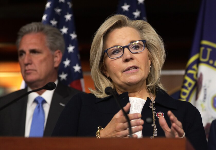 Liz Cheney speaks at a lectern with Kevin McCarthy behind her. 