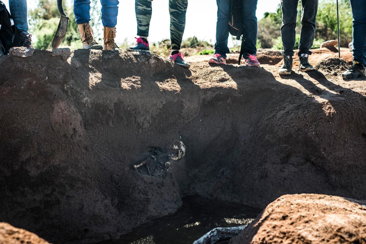 Members of the rastreadoras stand around the grave of a body unearthed on a mountainside in the state of Sinaloa.