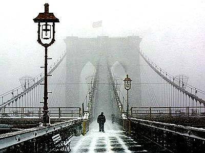 Pedestrians cross the snow-covered Brooklyn Bridge as the first major winter storm of the season hits the Northeast.