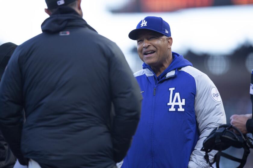 Los Angeles Dodgers manager Dave Roberts meets with umpires and San Francisco Giants manager Gabe Kapler to trade starting lineups before a baseball game, Friday, May 21, 2021, in San Francisco. (AP Photo/D. Ross Cameron)