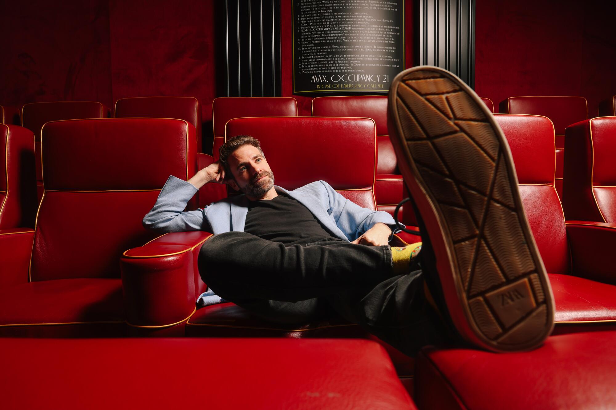 Ben Whitehair reclines  in a theater, foot kicked up in the foreground.
